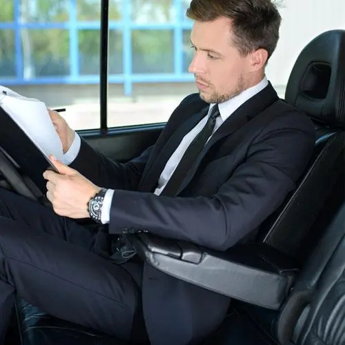 business man writing while sitting in car